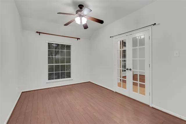 an empty room with wooden floor chandelier and windows