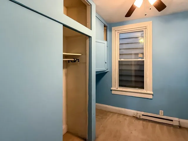 an empty room with closet and a chandelier fan