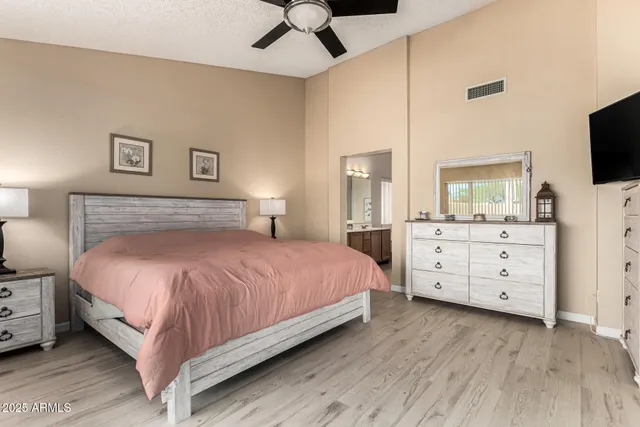 a bedroom with a bed and a flat tv screen on dresser
