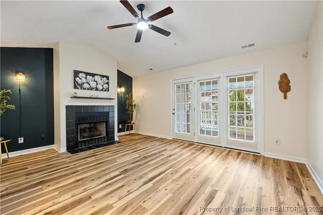 an empty room with windows fireplace and a ceiling fan