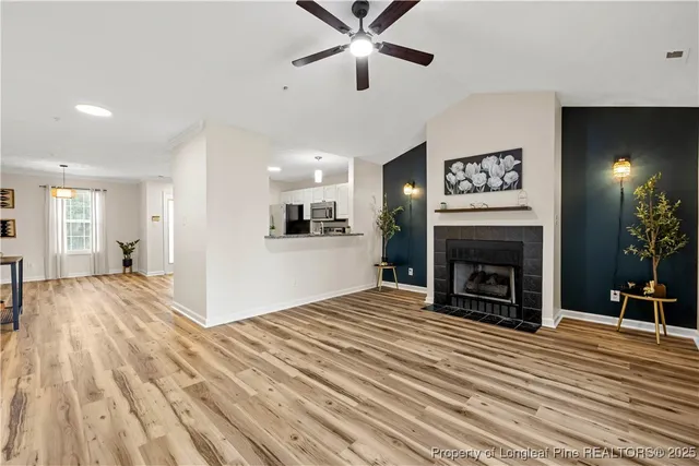 a view of an empty room with chandelier fan and kitchen view