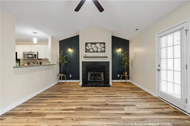 a view of a livingroom with wooden floor and a fireplace