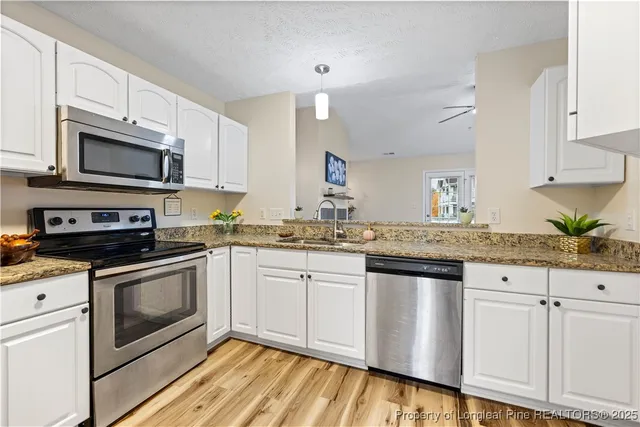 a kitchen with granite countertop white cabinets stainless steel appliances and a sink