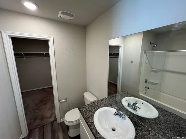a bathroom with a granite countertop sink toilet a mirror and shower