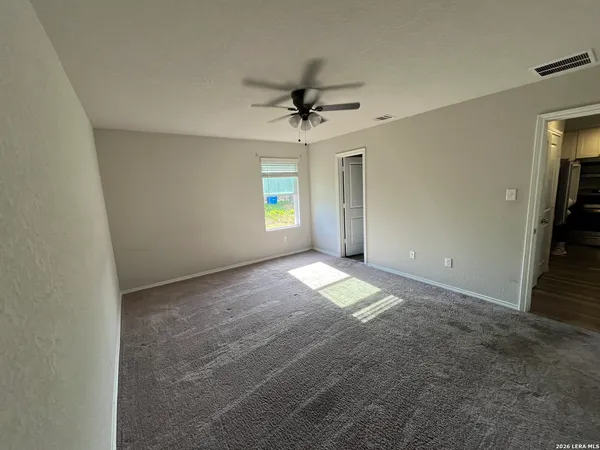 an empty room with windows and fan