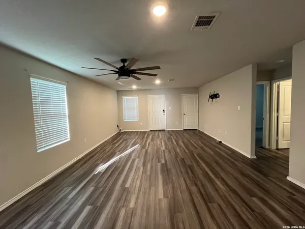 a view of empty room with wooden floor and fan