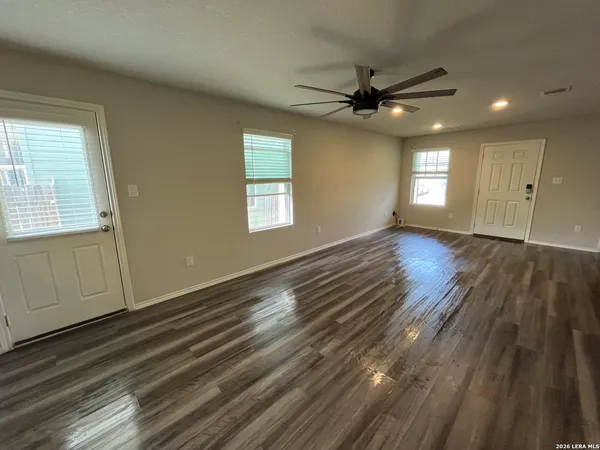 a view of an empty room with wooden floor and a window