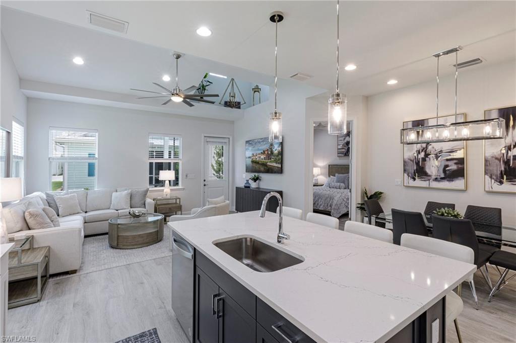 7138 Cayo Coco Lane Naples, FL 34113 - Photo 5 of 42 a kitchen with a dining table chairs sink and white cabinets
