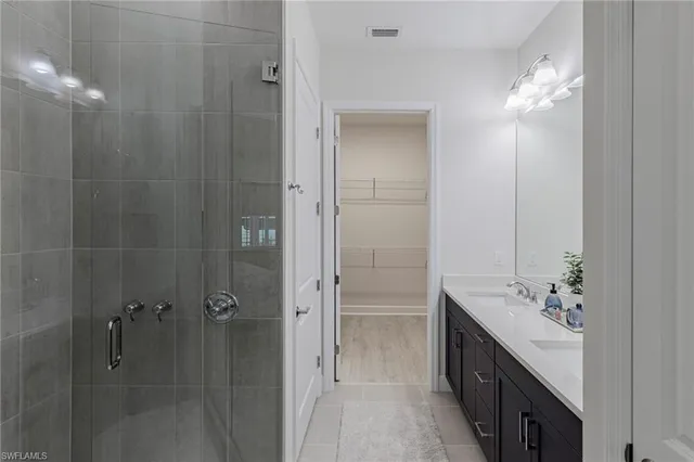 a bathroom with a double vanity sink a large mirror and shower