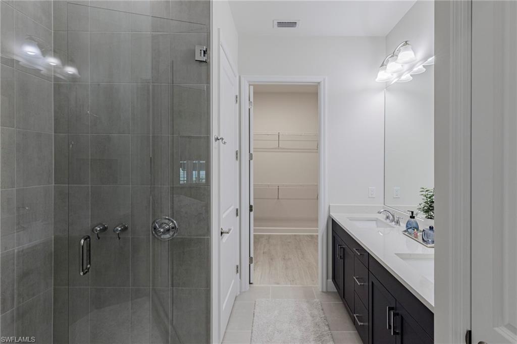 7138 Cayo Coco Lane Naples, FL 34113 - Photo 9 of 42 a bathroom with a double vanity sink a large mirror and shower