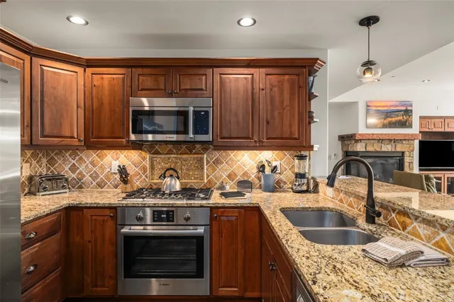 a kitchen with stainless steel appliances granite countertop a sink stove and microwave