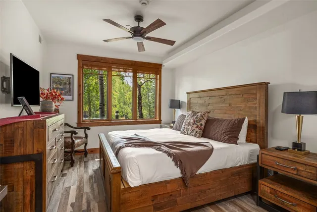 a bedroom with a bed a large window and flat screen tv