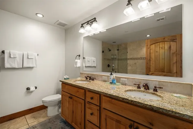 a bathroom with a granite countertop sink a toilet and a mirror
