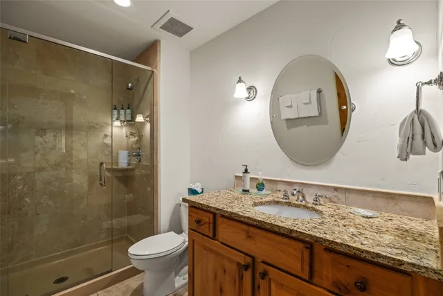 a bathroom with a granite countertop toilet a sink and a mirror
