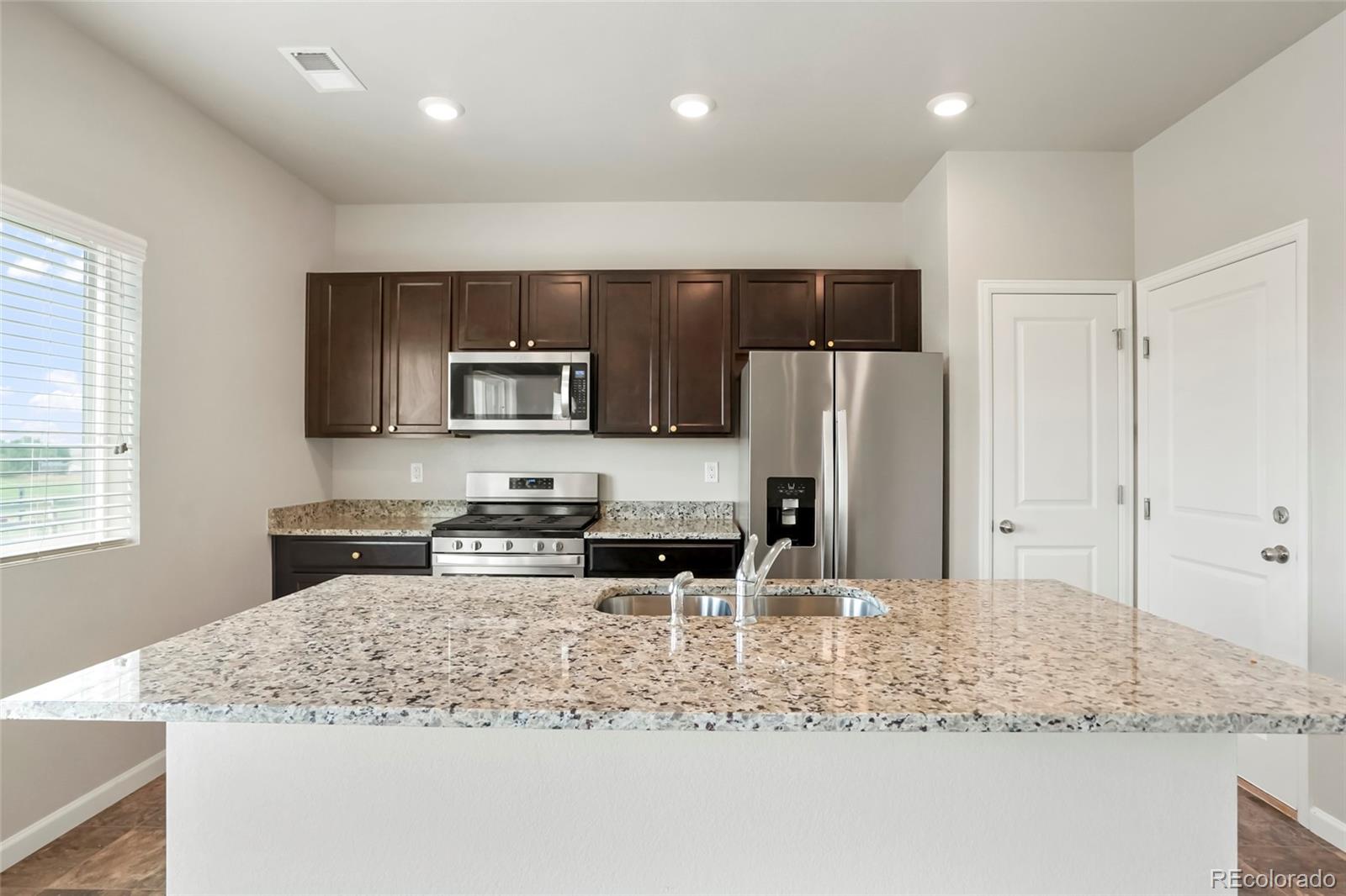 1843 Homestead Drive Fort Lupton, CO 80621 - Photo 19 of 33 a kitchen with stainless steel appliances granite countertop a sink refrigerator and microwave
