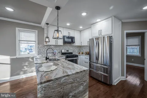 a kitchen with stainless steel appliances granite countertop a refrigerator a sink dishwasher a stove and white cabinets with wooden floor