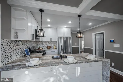 a kitchen with kitchen island granite countertop a sink and a refrigerator