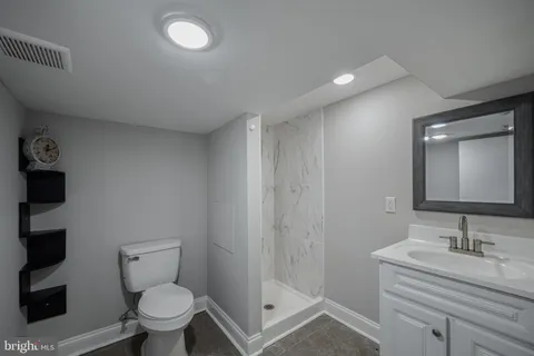a bathroom with a granite countertop sink a toilet and a mirror
