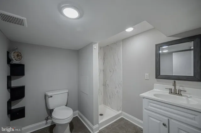 a bathroom with a granite countertop sink a toilet and a mirror