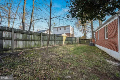 a view of backyard with wooden fence and large trees