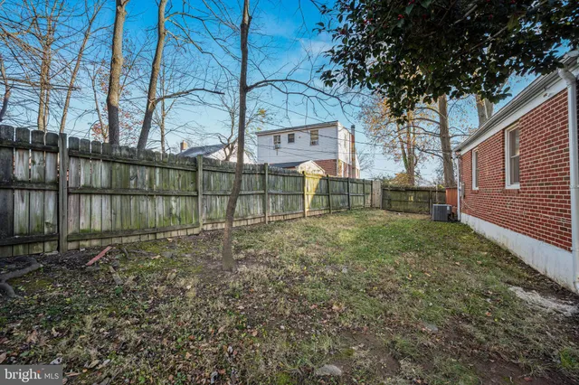 a view of backyard with wooden fence and large trees