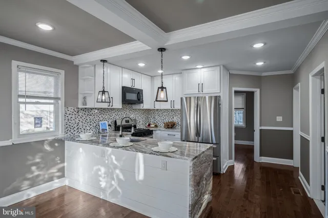 a kitchen with stainless steel appliances granite countertop a refrigerator a sink dishwasher a stove and white cabinets with wooden floor