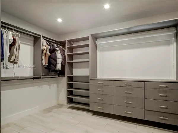 a view of walk in closet with clothes and shoes
