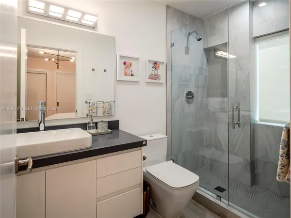a bathroom with a granite countertop sink a toilet and shower