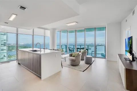 a living room with furniture a flat screen tv and a large window
