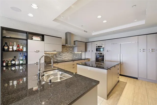 a kitchen with stainless steel appliances granite countertop a sink a stove top oven a counter space and cabinets