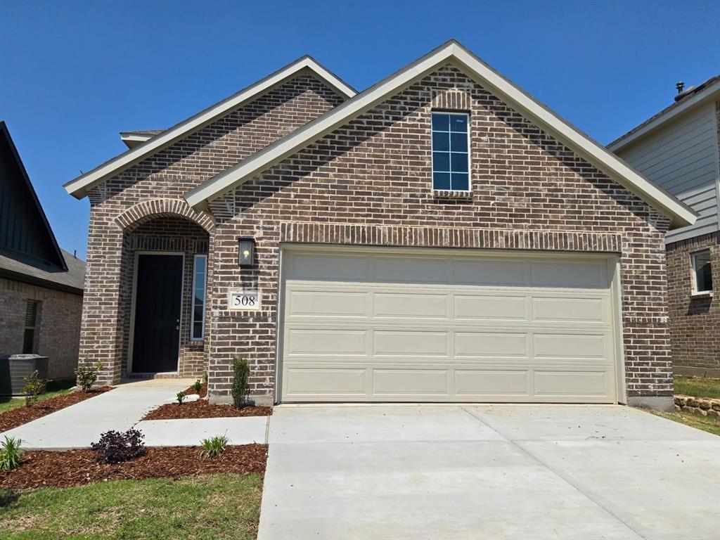 Traditional brick exterior featuring an arched entry, an integrated garage, and a concrete driveway