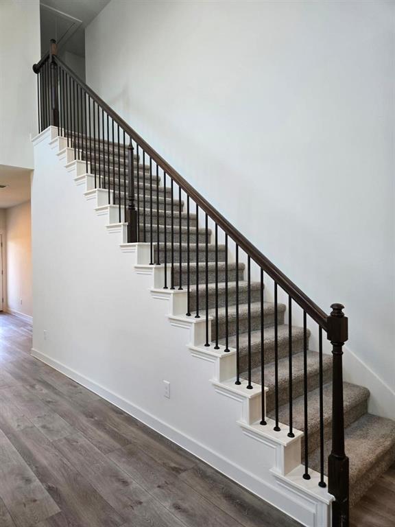 508 Weller Road McKinney, TX 75069 - Photo 8 of 16 Staircase featuring dark wood handrails and balusters, plush carpeted treads, and white risers