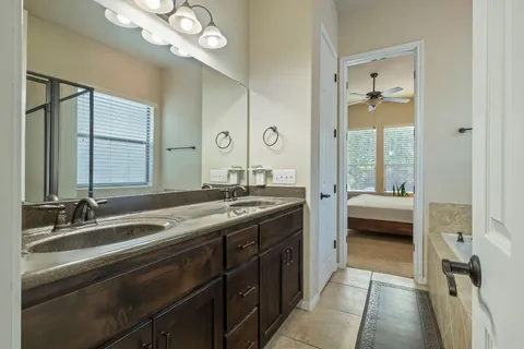 a en suite bathroom with a double vanity sink a mirror and a bathtub