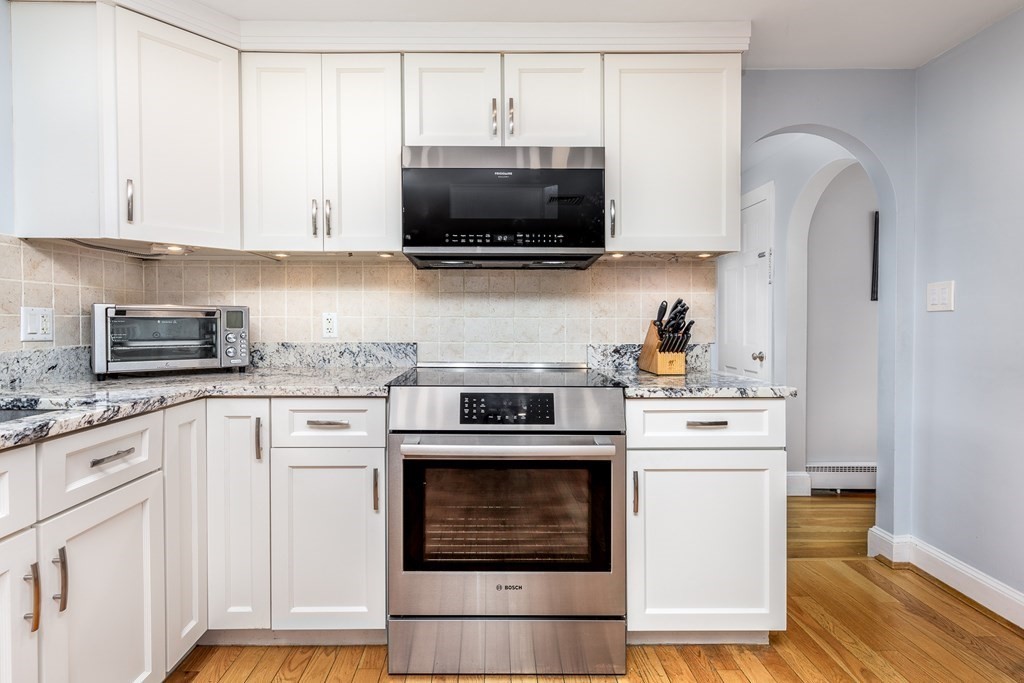 32 Norman Road Hamilton, MA 01982 - Photo 8 of 39 a kitchen with stainless steel appliances granite countertop a stove a microwave and white cabinets