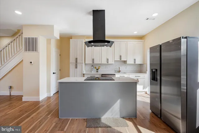 a kitchen with kitchen island stainless steel appliances a stove refrigerator sink and cabinets