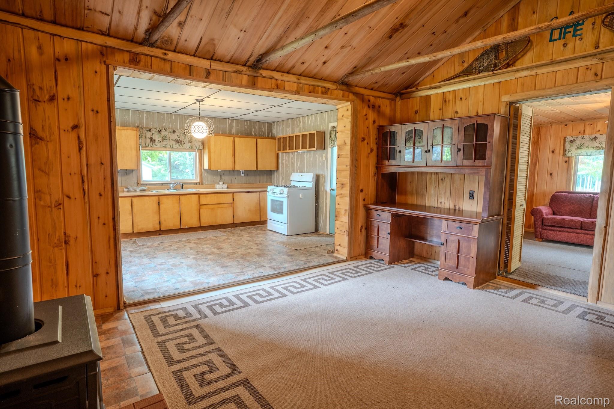 4350 Shrew Road Lincoln, MI 48742 - Photo 15 of 32 Open-concept living area featuring wood paneling, wood-finish flooring, and a decorative rug