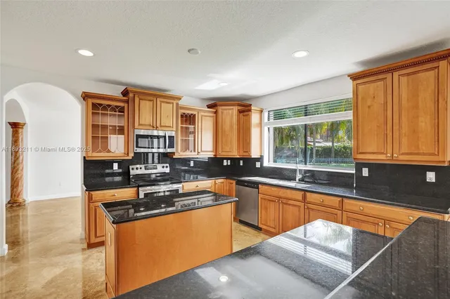 a kitchen with stainless steel appliances granite countertop a sink a stove and a refrigerator