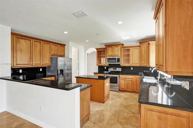 a kitchen with stainless steel appliances granite countertop a sink a stove and a refrigerator