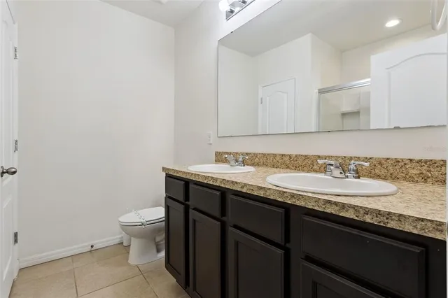a bathroom with a granite countertop sink and a toilet