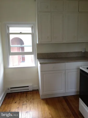 a kitchen with granite countertop white cabinets and a wooden floor