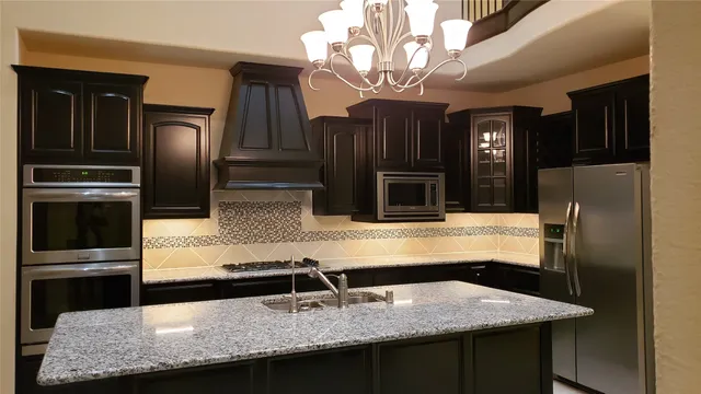 a kitchen with stainless steel appliances granite countertop a sink and a refrigerator
