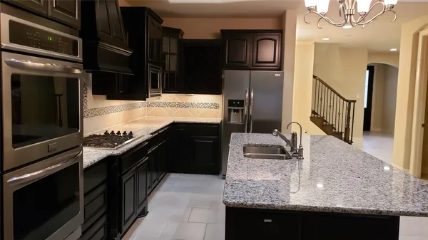 a kitchen with stainless steel appliances granite countertop a sink and a refrigerator