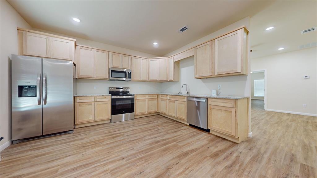 18636 Doubletree Drive Justin, TX 76247 - Photo 3 of 35 a kitchen with granite countertop a refrigerator and steel stainless steel appliances