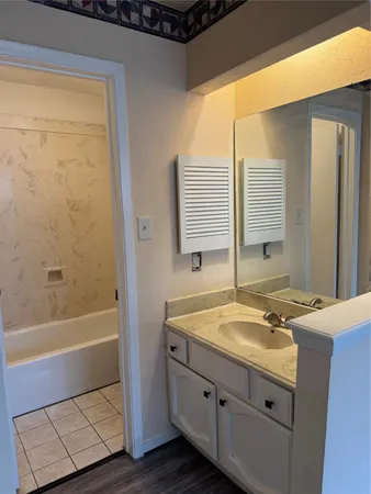 a bathroom with a granite countertop sink and a bathtub
