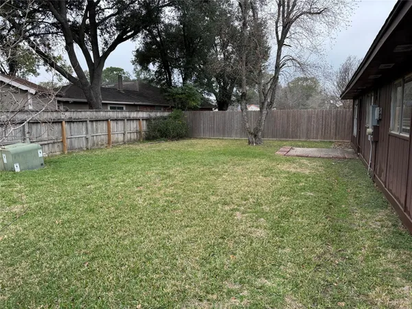 a view of backyard with wooden fence and a large tree