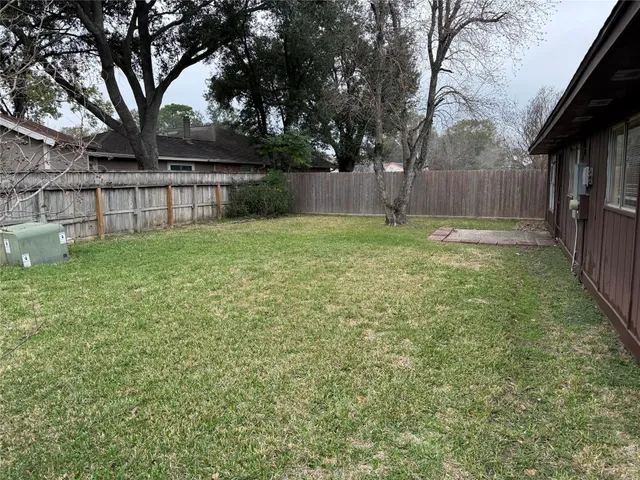 a view of backyard with wooden fence and a large tree