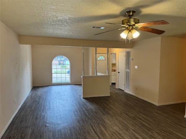 a view of an empty room with a window and wooden floor