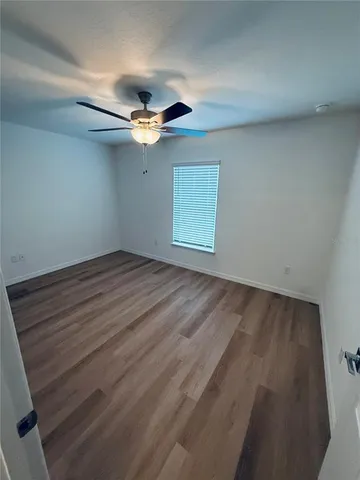 an empty room with a ceiling fan and wooden floor