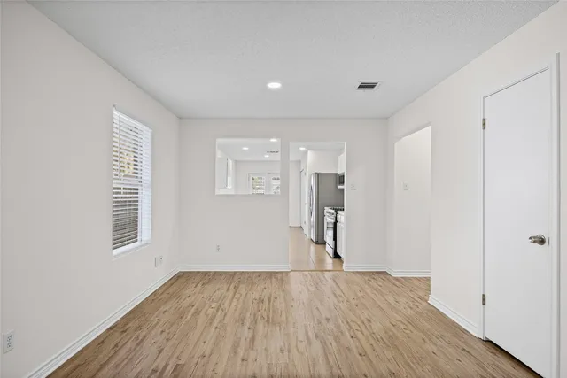 a view of an empty room with wooden floor and a ceiling fan