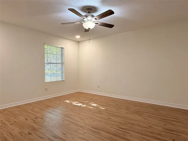 an empty room with wooden floor and ceiling fan